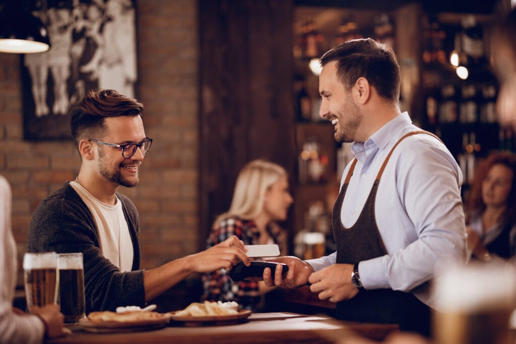 happy man using smart phone while making contactless payment waiter bar