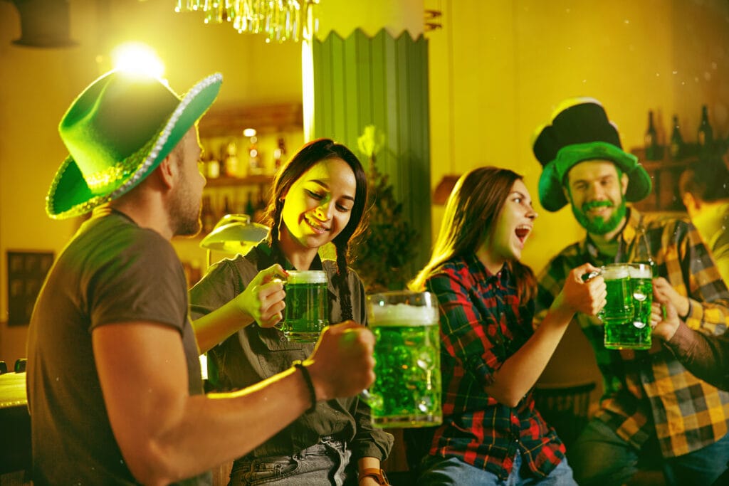 saint patrick s day party happy friends are celebrating drinking green beer young men women wearing green hats pub interior